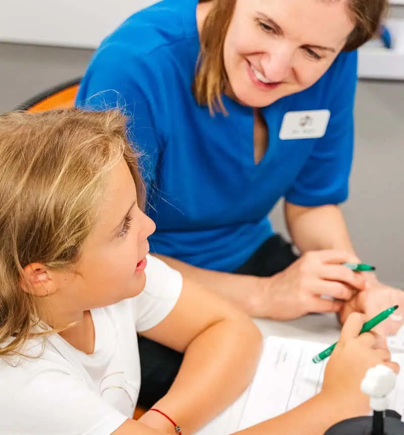 Young girl with pencil in hand working with adult on handwriting practice tasks