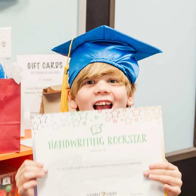 Happy young boy with graduation hat holding up Scribble 2 Script certification