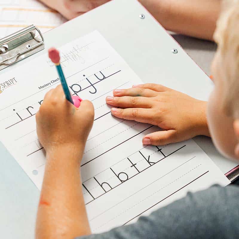 Boy being helped to practice writing with Scribble 2 Script exercises