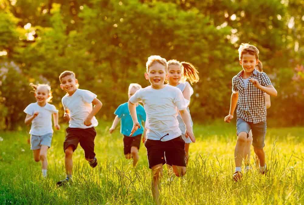 A group of happy children of boys and girls run in the Park on the grass on a Sunny summer day