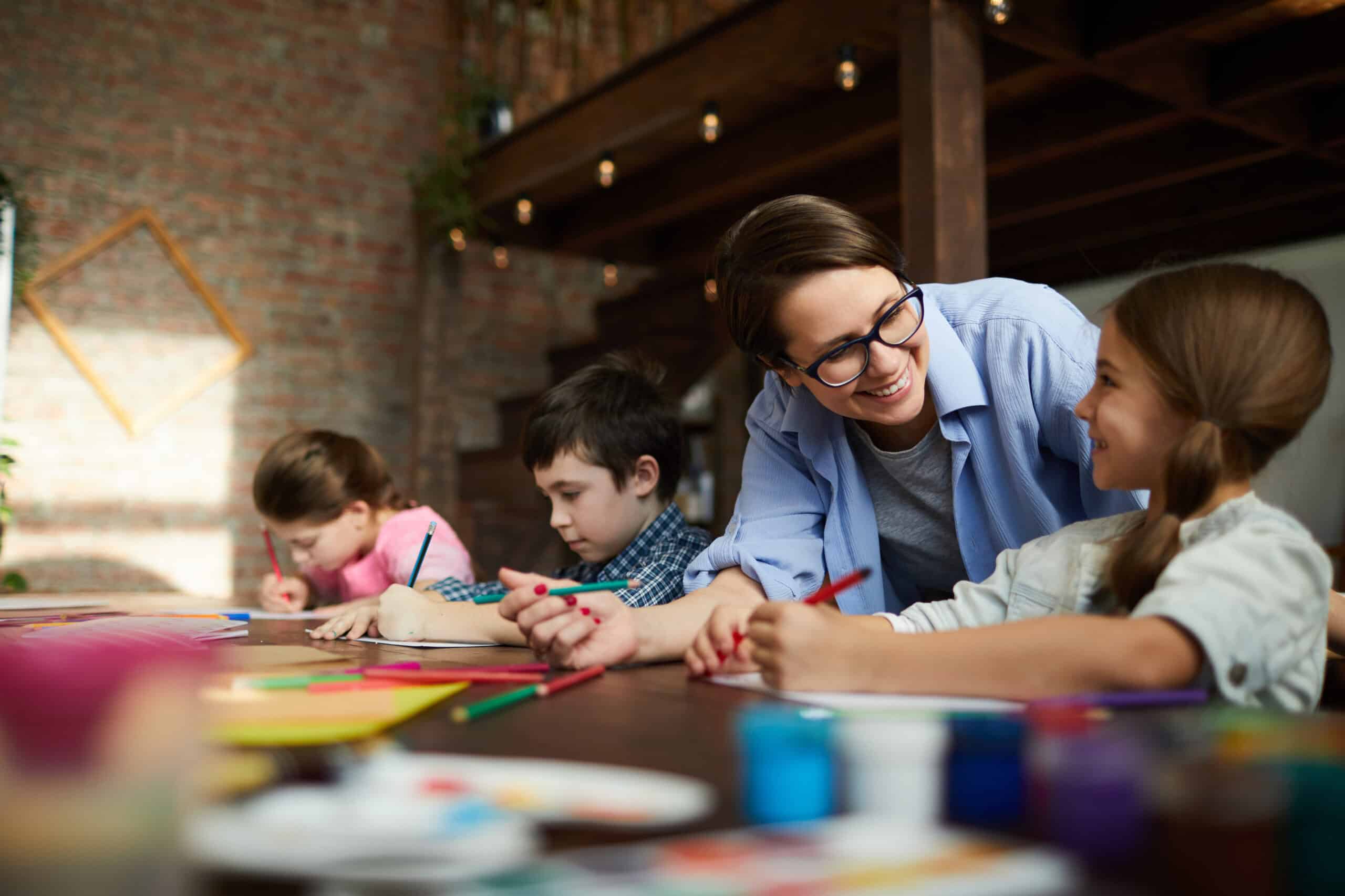 Portrait of smiling young woman working with kids in a class