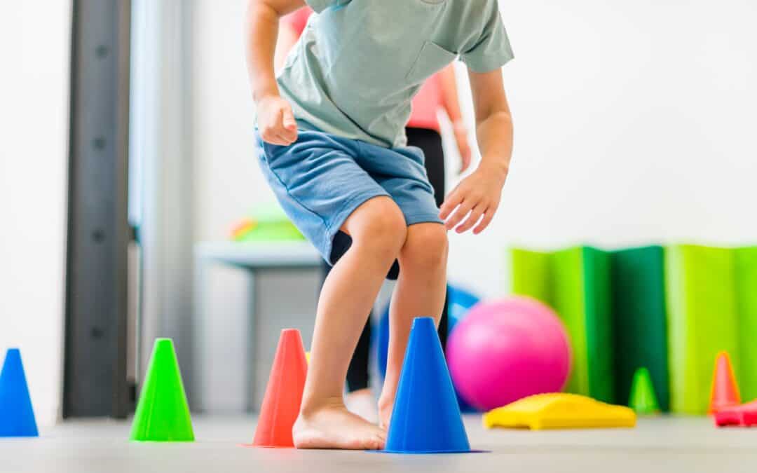 Young boy exercising with female physical therapist during therapy session. Child occupational physical therapy. Bilateral coordination.
